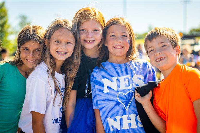 Five students smile during a homecoming parade